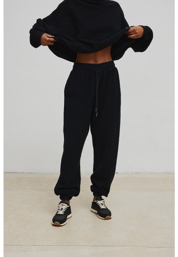 Marsala - Spodnie jogger o DELIKATNEJ STRUKTURZE w kolorze TOTALLY BLACK - AUSTIN-M. Stan: podwyższony. Materiał: dresówka, bawełna, dzianina, poliester. Styl: elegancki