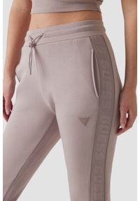 Guess - GUESS Dresowe damskie spodnie w kolorze taupe Allie Scuba. Kolor: beżowy. Materiał: dresówka