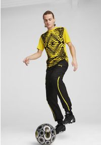 Puma - Męska koszulka przedmeczowa z krótkim rękawem Borussia Dortmund PUMA. Kolor: czarny, wielokolorowy, żółty. Długość rękawa: krótki rękaw. Długość: krótkie
