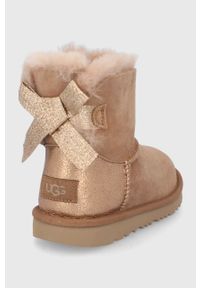 Ugg - UGG Śniegowce zamszowe dziecięce Mini Bailey Bow Glitz kolor brązowy. Nosek buta: okrągły. Kolor: brązowy. Materiał: zamsz. Szerokość cholewki: normalna