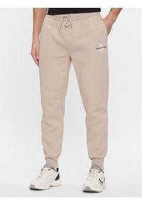 Calvin Klein Jeans Spodnie dresowe Monologo J30J324685 Beżowy Regular Fit. Kolor: beżowy. Materiał: syntetyk, dresówka, bawełna