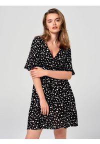 Sinsay - Sukienka mini w kropki z kopertowym dekoltem - czarny. Kolor: czarny. Materiał: skóra, wiskoza. Wzór: kropki. Typ sukienki: kopertowe. Długość: mini #1