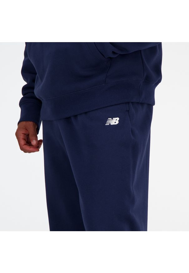 Spodnie męskie New Balance MP41519NNY – granatowe. Kolor: niebieski. Materiał: poliester, dresówka, bawełna. Wzór: haft