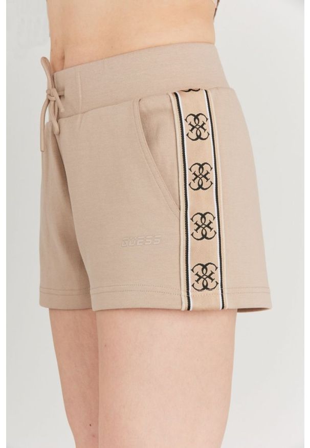 Guess - GUESS Beżowe szorty damskie z lampasami w logo. Kolor: beżowy. Materiał: bawełna. Wzór: aplikacja
