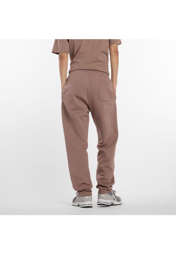 Spodnie męskie New Balance MP53508EAS – brązowe. Kolor: brązowy. Materiał: poliester, bawełna, dresówka, materiał. Wzór: napisy, aplikacja