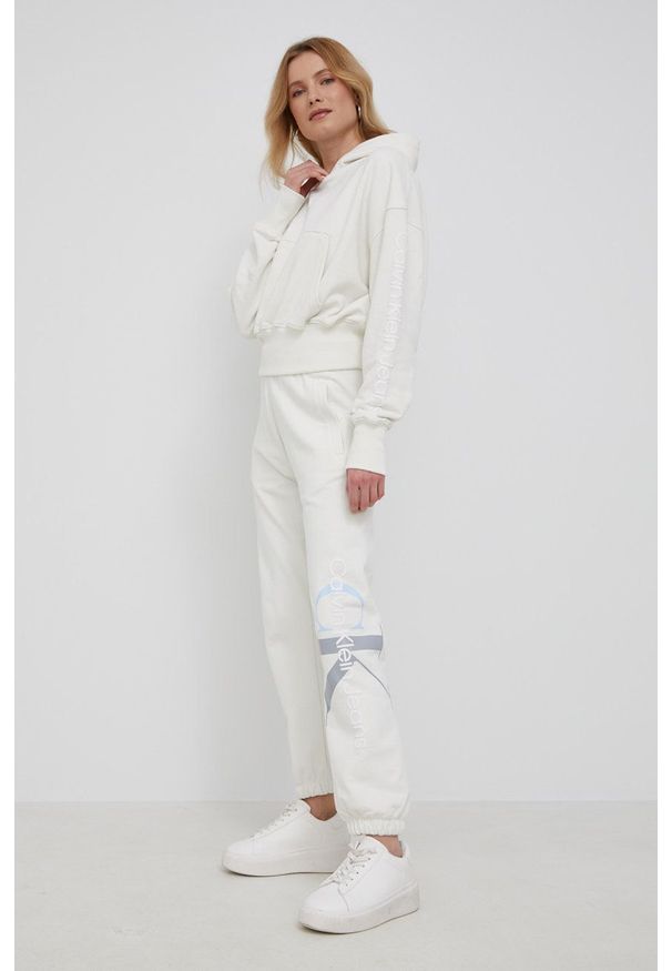 Calvin Klein Jeans Bluza bawełniana damska kolor beżowy z kapturem z nadrukiem. Okazja: na co dzień. Typ kołnierza: kaptur. Kolor: beżowy. Materiał: bawełna. Długość rękawa: długi rękaw. Długość: długie. Wzór: nadruk. Styl: casual