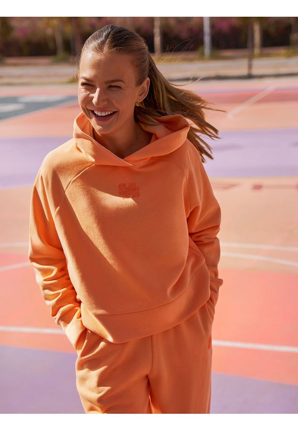 4f - Bluza dresowa z bawełną organiczną damska 4F x Anna Lewandowska. Okazja: na co dzień. Typ kołnierza: kaptur. Kolor: pomarańczowy. Materiał: bawełna, dresówka. Długość rękawa: raglanowy rękaw. Wzór: nadruk. Styl: sportowy, casual