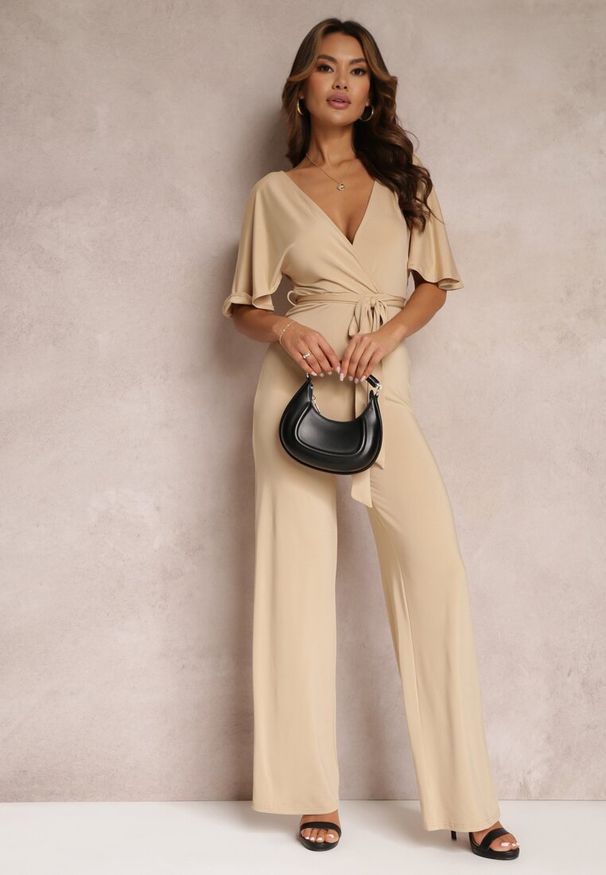 Renee - Beżowy Długi Kombinezon z Wiązaniem i Głębokim Kopertowym Dekoltem Sumya. Okazja: na spotkanie biznesowe. Kolor: beżowy. Długość: długie. Styl: biznesowy, elegancki