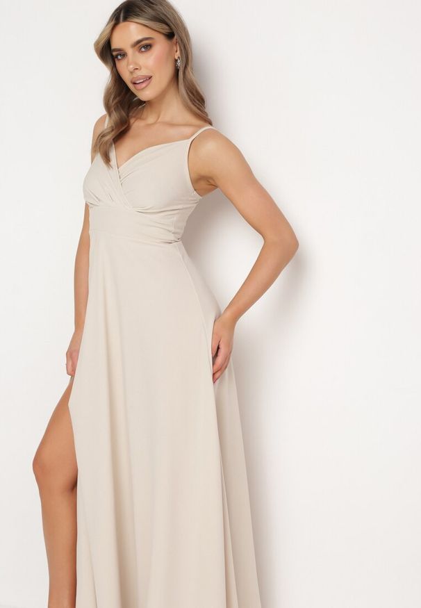 Born2be - Beżowa Rozkloszowana Klasyczna Sukienka z Kopertowym Dekoltem na Cienkich Ramiączkach z Rozcięciem Vinelia. Typ kołnierza: dekolt kopertowy. Kolekcja: dla wysokich. Kolor: beżowy. Długość rękawa: na ramiączkach. Typ sukienki: kopertowe. Styl: klasyczny. Długość: maxi