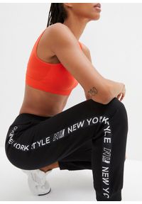 bonprix - Spodnie dresowe ze ściągaczem w talii i u dołu nogawek z napisem. Kolor: czarny. Materiał: dresówka. Wzór: napisy #2