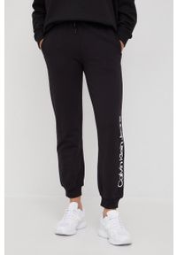 Calvin Klein Jeans spodnie dresowe bawełniane damskie kolor czarny z nadrukiem. Stan: podwyższony. Kolor: czarny. Materiał: dresówka, bawełna. Wzór: nadruk