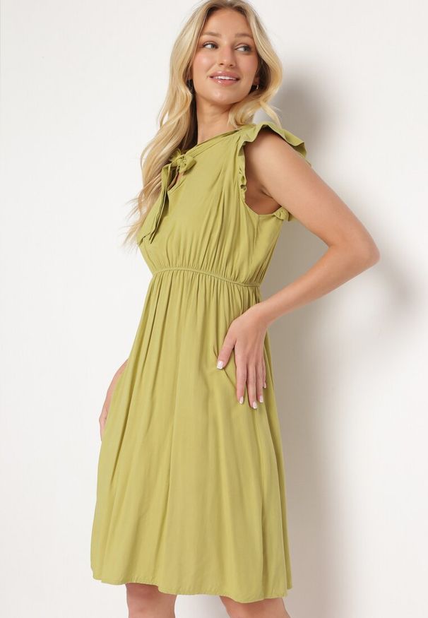 Born2be - Jasnozielona Rozkloszowana Sukienka z Wiązanym Dekoltem i Gumką w Pasie Ozdobiona Falbanką Dimonima. Kolor: zielony. Materiał: wiskoza, bawełna. Wzór: aplikacja. Typ sukienki: rozkloszowane. Styl: retro, elegancki