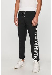 Calvin Klein Jeans - Spodnie. Kolor: czarny. Materiał: tkanina, poliamid, elastan. Wzór: nadruk #1