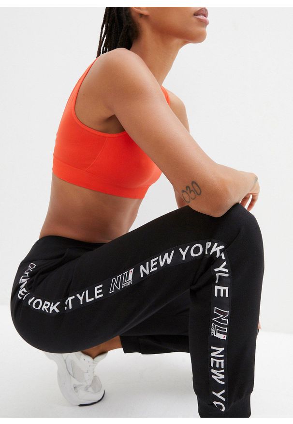 bonprix - Spodnie dresowe ze ściągaczem w talii i u dołu nogawek z napisem. Kolor: czarny. Materiał: dresówka. Wzór: napisy