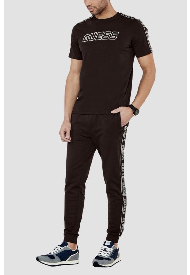 Guess - GUESS Brązowe męskie spodnie dresowe z lampasami New Arlo, Rozmiar XXL. Kolor: brązowy. Materiał: dresówka