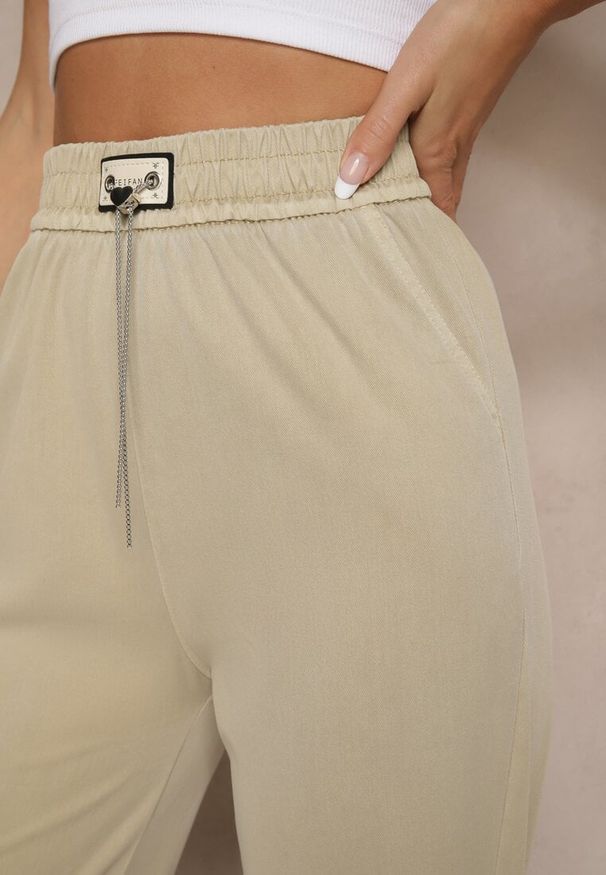 Renee - Beżowe Spodnie z Wiskozą High Waist z Ozdobną Aplikacją Frovanna. Okazja: na co dzień. Stan: podwyższony. Kolor: beżowy. Materiał: wiskoza. Wzór: aplikacja. Styl: klasyczny, elegancki, casual