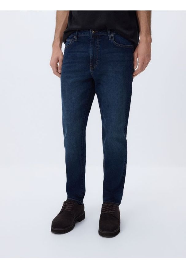 Reserved - Jeansy carrot slim z efektem sprania - granatowy. Kolor: niebieski
