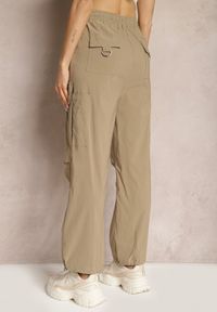 Renee - Ciemnobeżowe Szerokie Spodnie High Waist w Stylu Bojówek Wykończone Gumką w Talii Ellcara. Okazja: na co dzień. Stan: podwyższony. Kolor: beżowy. Materiał: satyna. Wzór: moro. Styl: elegancki, sportowy, militarny, wizytowy, casual #4