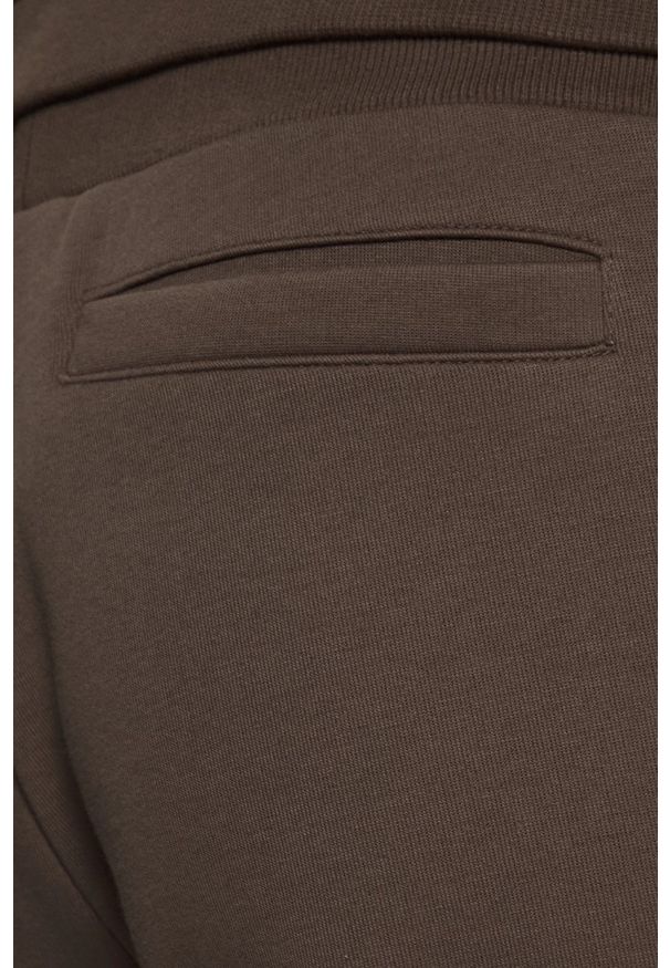 Guess - GUESS Brązowe męskie spodnie dresowe z lampasami Mickey, Rozmiar S. Kolor: brązowy. Materiał: dresówka