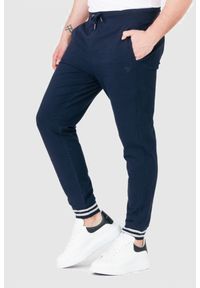 Guess - GUESS Granatowe męskie spodnie dresowe. Kolor: niebieski. Materiał: bawełna. Wzór: aplikacja