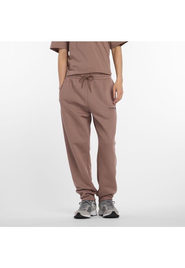 Spodnie męskie New Balance MP53508EAS – brązowe. Kolor: brązowy. Materiał: dresówka, materiał, poliester, bawełna. Wzór: aplikacja, napisy