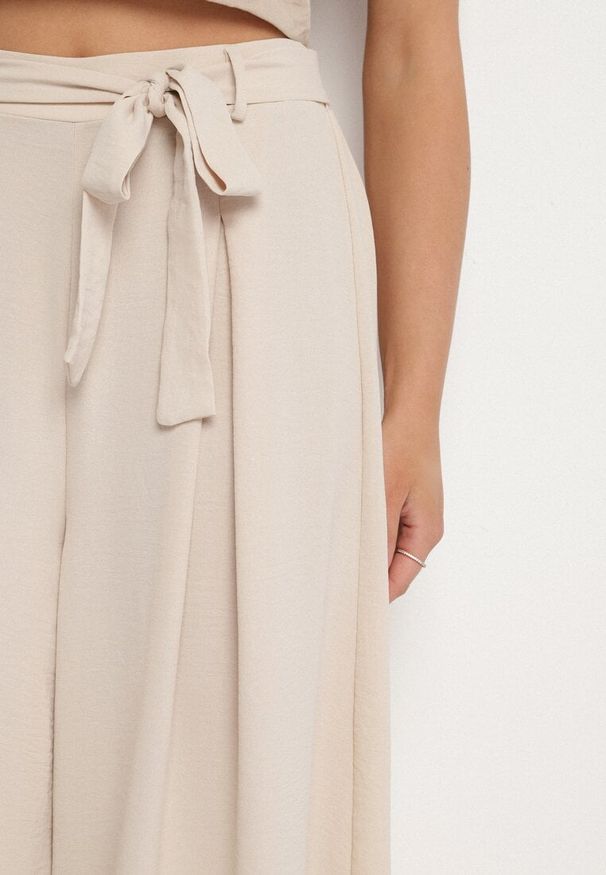 Born2be - Beżowe Szerokie Spodnie z Bawełną i Wysokim Stanem Ozdobione Paskiem Seleldi. Okazja: na co dzień. Stan: podwyższony. Kolor: beżowy. Materiał: bawełna. Wzór: aplikacja. Styl: klasyczny, casual