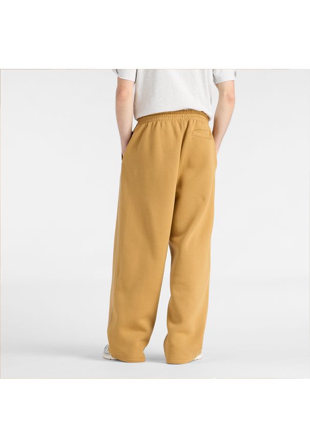 Spodnie męskie New Balance MB61M77EABG – pomarańczowe. Kolor: pomarańczowy. Materiał: materiał, bawełna, dresówka, poliester. Wzór: napisy, aplikacja