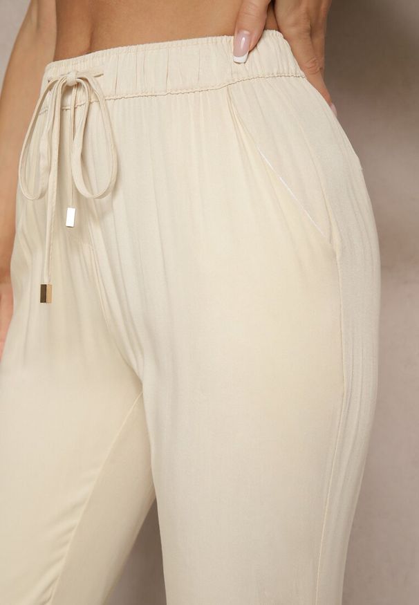 Renee - Jasnobeżowe Spodnie Dresowe High Waist z Ozdobnym Wiązaniem Ellivaria. Okazja: na co dzień. Stan: podwyższony. Kolor: beżowy. Materiał: dresówka. Styl: casual