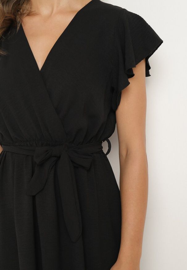 Born2be - Czarna Kopertowa Sukienka z Asymetrycznym Dołem Ozdobiona Falbanką z Paskiem w Talii Snidia. Okazja: na co dzień, na spacer. Kolor: czarny. Wzór: aplikacja. Sezon: lato. Typ sukienki: asymetryczne, kopertowe. Styl: elegancki, klasyczny, casual
