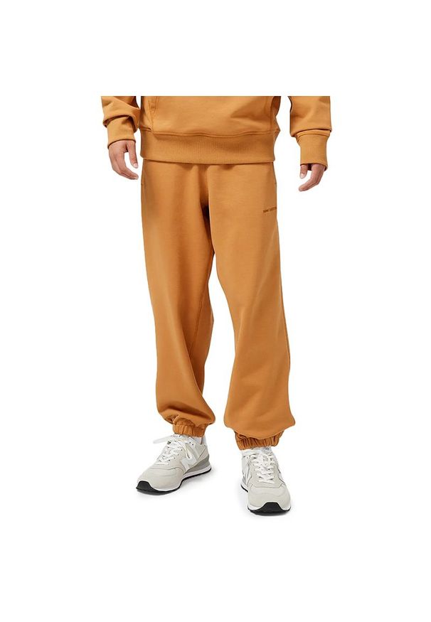 Spodnie dresowe New Balance MP23551TOB - pomarańczowe. Kolor: pomarańczowy. Materiał: dresówka