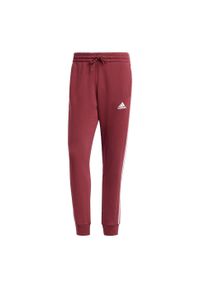 Adidas - Spodnie Essentials Fleece 3-Stripes Tapered Cuff. Kolor: czerwony. Materiał: polar, materiał