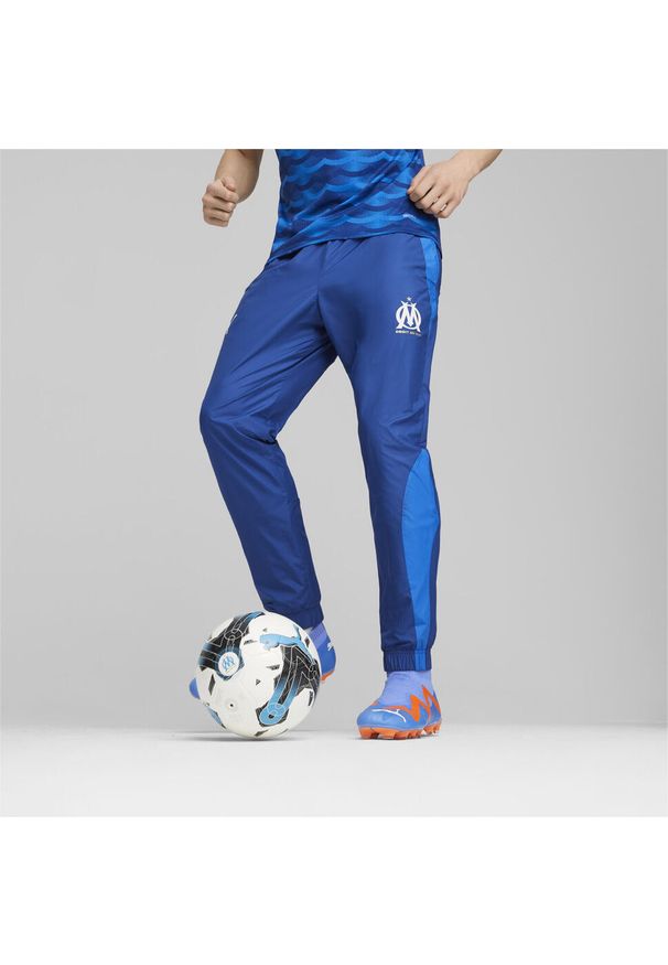 Puma - Tkane spodnie dresowe Prematch om 2023/24. Kolor: niebieski. Materiał: dresówka