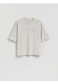 Reserved - T-shirt boxy z naszywką - złamana biel. Materiał: dzianina, bawełna. Wzór: aplikacja #1