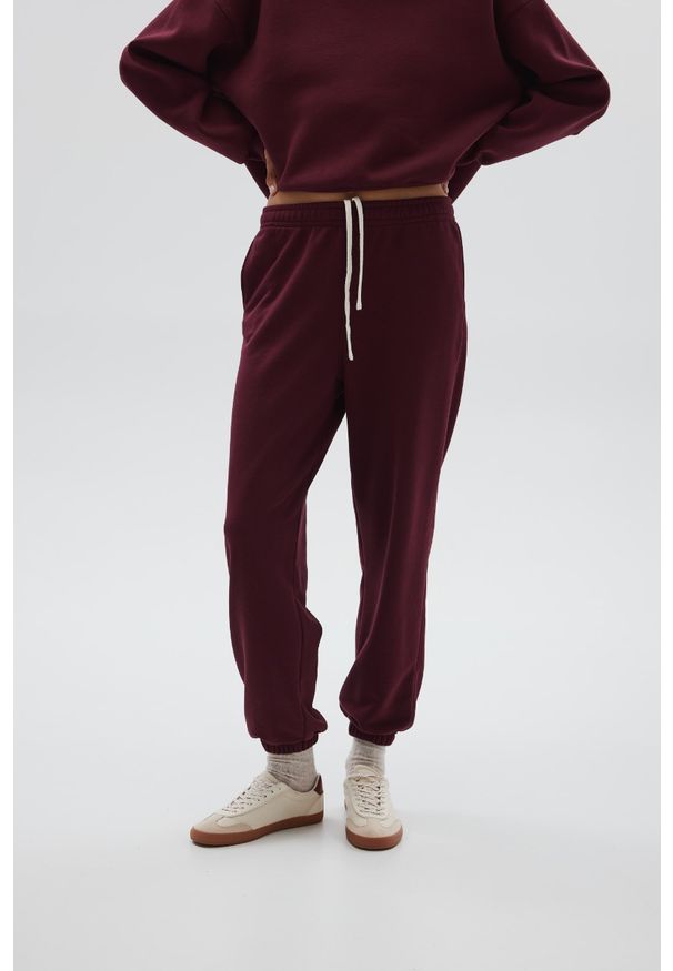 Marsala - Spodnie typu jogger w kolorze BURGUNDY - COOL-XS. Stan: podwyższony. Materiał: guma, dzianina, poliester, dresówka, bawełna. Styl: elegancki