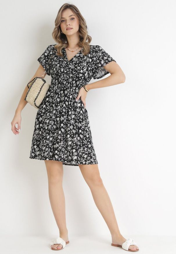 Born2be - Czarna Kwiecista Sukienka Mini z Wiskozy z Marszczoną Gumką w Pasie Catela. Kolor: czarny. Materiał: wiskoza. Długość rękawa: krótki rękaw. Wzór: kwiaty. Sezon: wiosna, lato. Typ sukienki: kopertowe, rozkloszowane. Długość: mini
