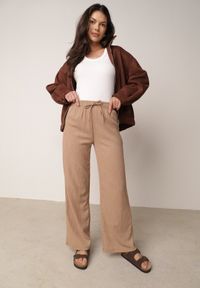 Born2be - Beżowe Szerokie Spodnie z Teksturalnej Tkaniny z Wiązaniem w Pasie Agatia. Okazja: do pracy, na co dzień, na spacer. Stan: podwyższony. Kolor: beżowy. Materiał: tkanina. Długość: długie. Styl: wakacyjny, casual #1