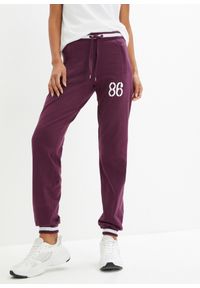 bonprix - Spodnie dresowe z zapinanymi kieszeniami. Kolor: fioletowy. Materiał: dresówka. Wzór: nadruk. Styl: sportowy #1