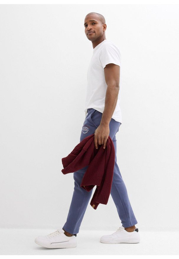 bonprix - Spodnie sportowe ze sportowymi detalami. Kolor: niebieski. Materiał: bawełna. Wzór: nadruk. Styl: sportowy