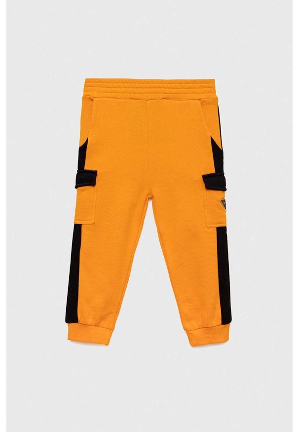 Guess spodnie dresowe bawełniane dziecięce kolor pomarańczowy wzorzyste. Stan: podwyższony. Kolor: pomarańczowy. Materiał: bawełna, dresówka