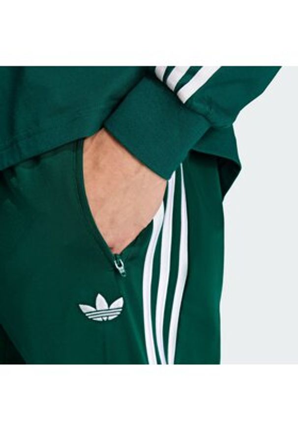 Adidas - adidas Spodnie dresowe Firebird KD8317 Zielony Loose Fit. Kolor: zielony. Materiał: syntetyk