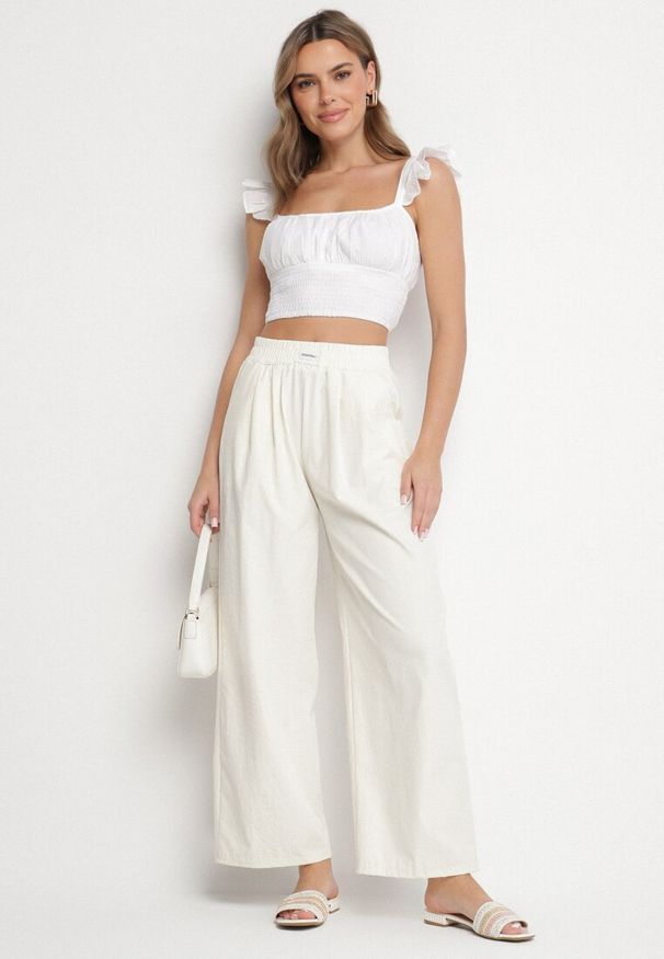 Born2be - Jasnobeżowe Szerokie Spodnie z Bawełną Wysokim Stanem i Naszywką Nannirea. Okazja: na co dzień. Stan: podwyższony. Kolor: beżowy. Materiał: bawełna. Wzór: aplikacja. Styl: casual, elegancki, klasyczny