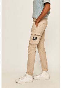 Calvin Klein Jeans - Spodnie. Kolor: beżowy. Materiał: tkanina, bawełna, elastan. Wzór: gładki #4