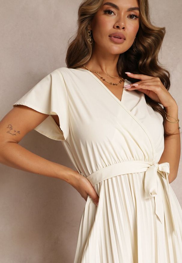 Renee - Jasnobeżowa Koktajlowa Maxi Sukienka Ozdobiona Plisami z Trójkątnym Dekoltem i Wiązaniem w Talii Phoelia. Okazja: na imprezę. Kolor: beżowy. Wzór: aplikacja. Styl: wizytowy. Długość: maxi