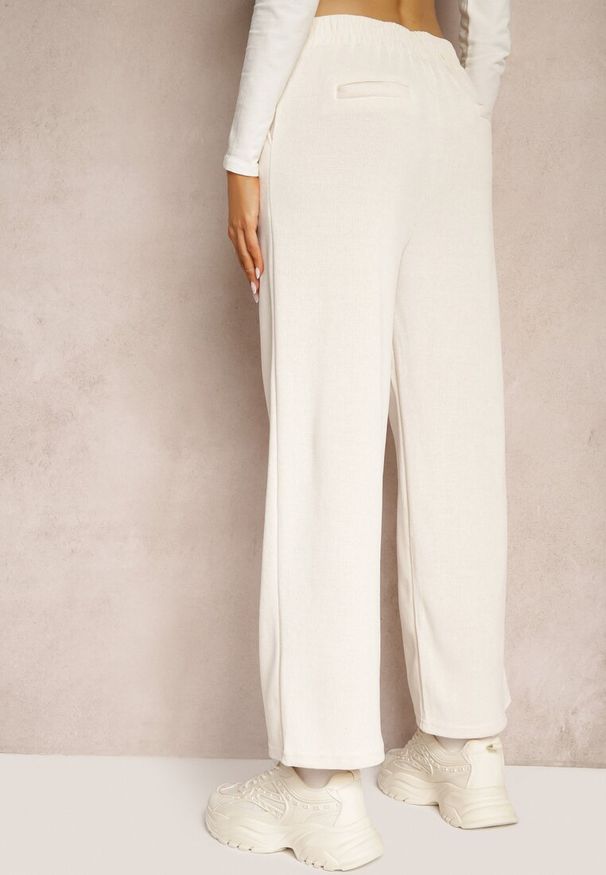 Renee - Jasnobeżowe Szerokie Spodnie Ozdobione Imitacją Kieszeni Tassae. Okazja: na co dzień. Stan: podwyższony. Kolor: beżowy. Materiał: bawełna. Wzór: aplikacja. Styl: casual, elegancki