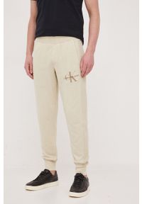 Calvin Klein Jeans spodnie dresowe bawełniane kolor beżowy gładkie. Kolor: beżowy. Materiał: bawełna, dresówka. Wzór: gładki #2