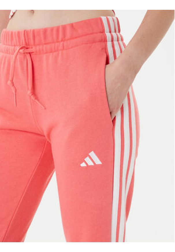 Adidas - adidas Spodnie dresowe Essentials 3-Stripes KE4387 Koralowy Regular Fit. Kolor: pomarańczowy. Materiał: bawełna