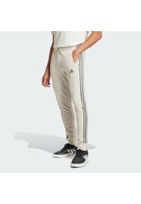 Adidas - Spodnie Essentials French Terry Tapered Cuff 3-Stripes. Kolor: zielony, szary, wielokolorowy. Materiał: dresówka. Sport: taniec, joga i pilates #1