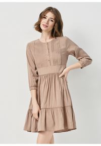 Ochnik - Beżowa plisowana sukienka mini. Kolor: beżowy. Materiał: wiskoza. Typ sukienki: rozkloszowane, proste. Długość: mini