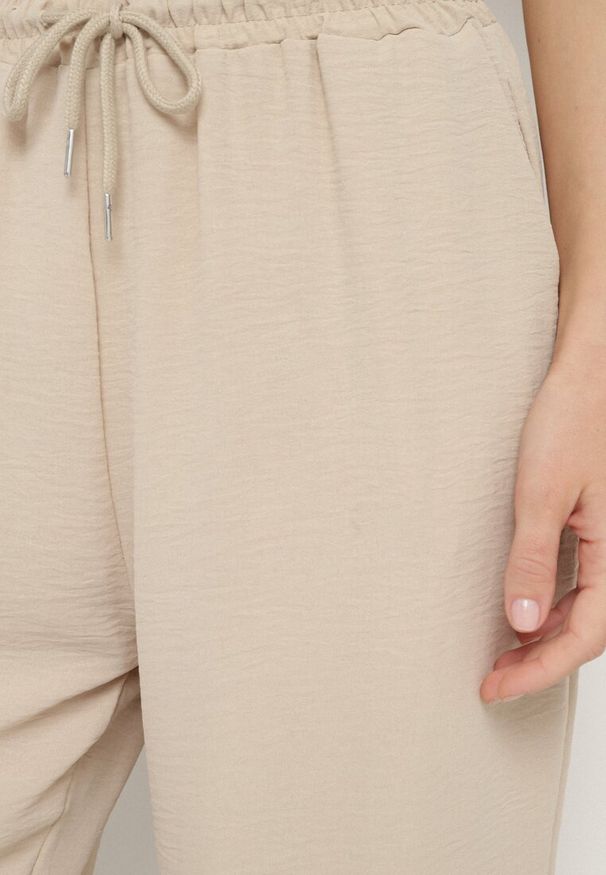 Born2be - Beżowe Spodnie Luźne z Kieszeniami i Gumką w Talii oraz Sznurkiem Enivia. Okazja: na co dzień. Kolor: beżowy. Styl: elegancki, casual