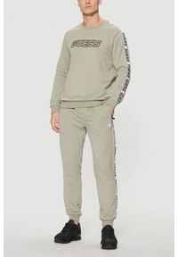 Guess - GUESS Zielone męskie spodnie dresowe z lampasami New Arlo. Kolor: zielony. Materiał: dresówka